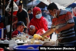 Seorang perempuan mengenakan masker untuk mencegah penularan COVID-19 sedang berbelanja di sebuah pasar tradisional di Jakarta, 1 Maret 2021. (Foto: Willy Kurniawan/Reuters)