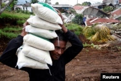 Seorang sukarelawan membopong karung beras untuk dibagikan kepada warga desa yang terdampak gempa di Serampad, Cianjur, Jawa Barat, 26 November 2022.(Antara Foto/Wahyu Putro A/ via REUTERS).