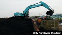 Sebuah alat berat terlihat mengeruk batu bara untuk dipindahkan ke dalam truk-truk pengangkut di Pelabuhan Karya Citra Nusantara di Jakarta Utara, pada 13 Januari 2022. (Foto: Reuters/Willy Kurniawan)
