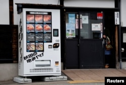 Menu mesin penjual otomatis yang menawarkan daging Beruang Hitam Asia, Daging Sapi Akita, dan ikan sungai kering terlihat di depan restoran Mie Soba di Semboku, prefektur Akita, Jepang, 6 April 2023. (REUTERS/Irene Wang)