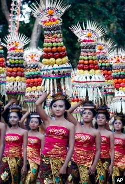 Perempuan Bali dalam pakaian tradisional membawa sesajen di kepala mereka pada parade untuk menandai Pesta Kesenian Bali di Bali, Jumat, 13 Juni 2014. (AP/Firdia Lisnawati)