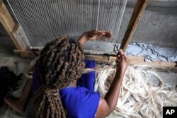 Seorang pekerja menganyam karpet menggunakan benang serat pisang di pabrik Texfad di Sonde, Distrik Mukono, Uganda, Rabu, 20 September 2023. (AP/Hajarah Nalwadda)