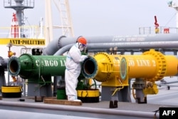 Seorang petugas inspeksi memeriksa sebuah kapal tanker yang membawa minyak mentah impor di Pelabuhan Qingdao di Provinsi Shandong timur China, 9 Mei 2022. (Foto: AFP)