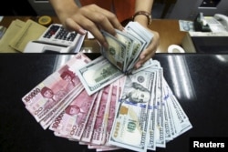 Seorang teller di money changer menghitung mata dolar AS di Jakarta, 12 Agustus 201. (Foto: REUTERS)